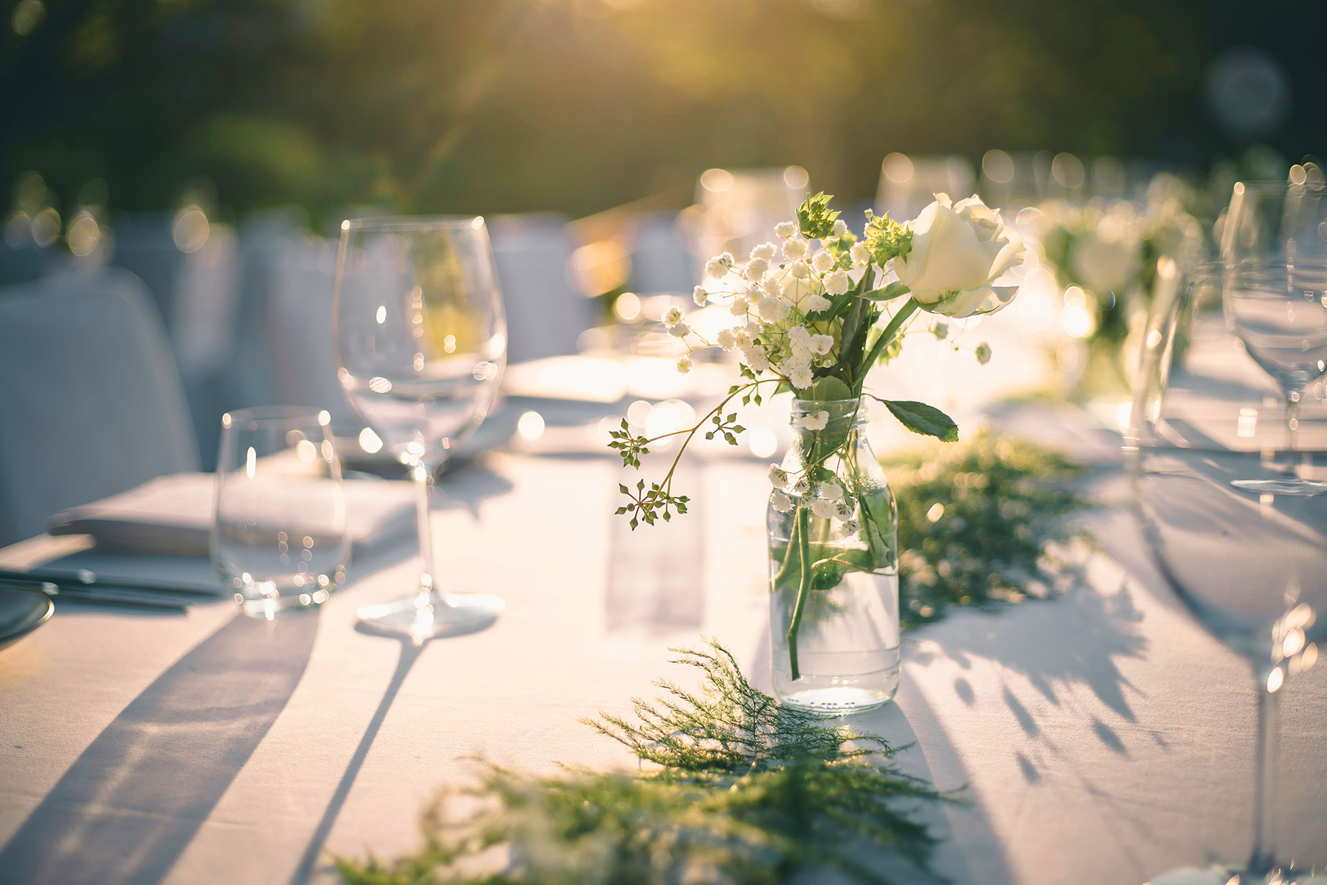 Outdoor event table set with white flowers and wine glasses